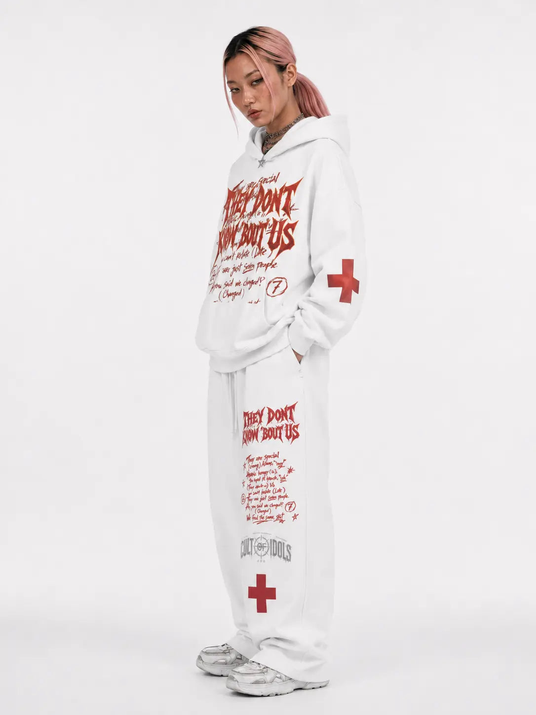 Person wearing a white hoodie and pants with text and red cross symbols on a white background