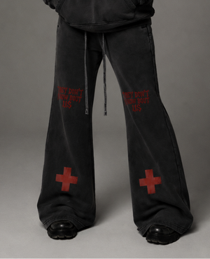 Person wearing a black hoodie and pants with red text and symbols on a gray background