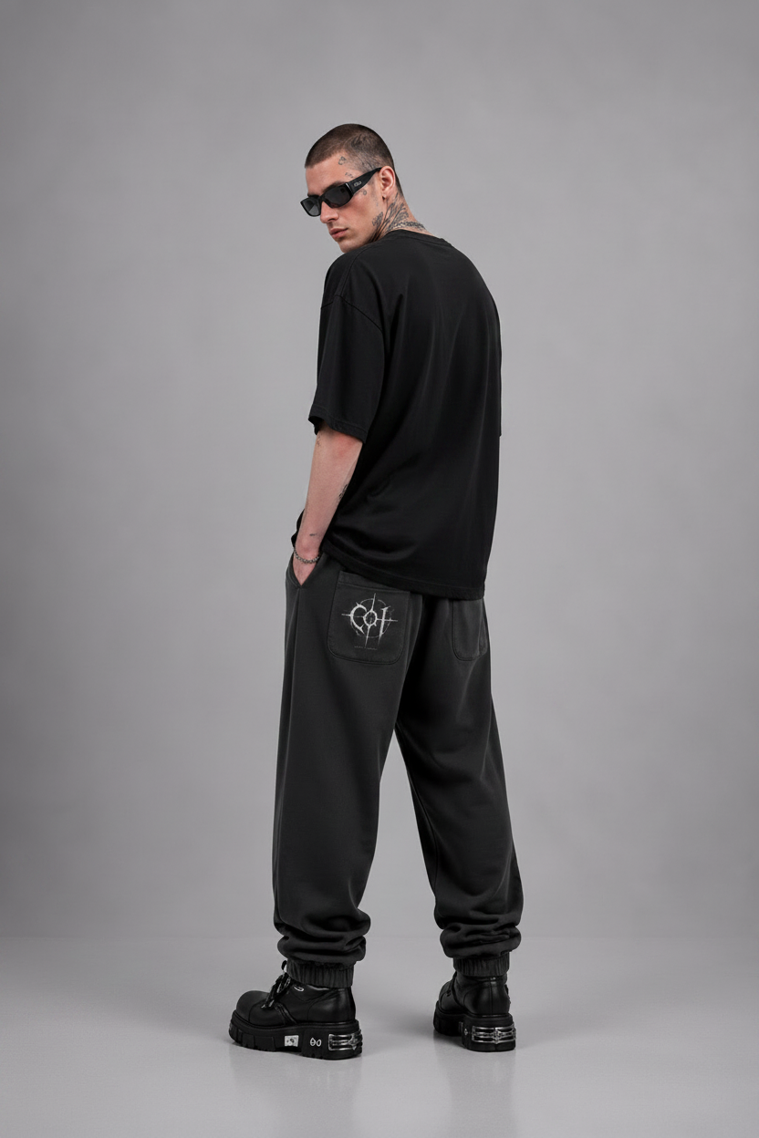 Man wearing black clothing with logos on a gray background