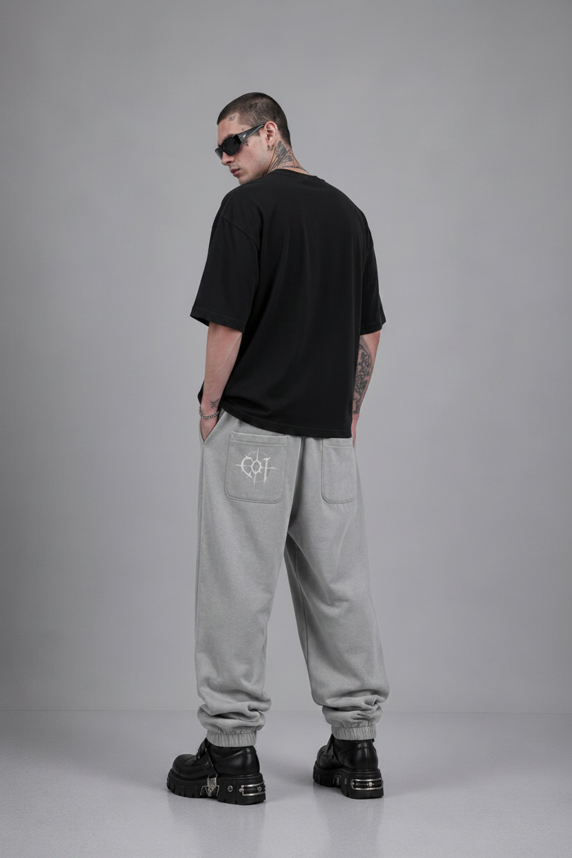 Person wearing a black graphic t-shirt and gray sweatpants on a gray background
